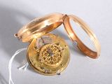 a gold pocket watch sitting on a white surface