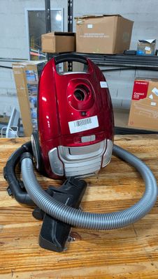 un aspirateur rouge posé sur une table en bois