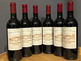 four bottles of wine are lined up on a wooden barrel