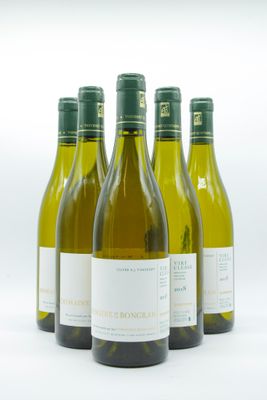 quatre bouteilles de vin blanc sont alignées sur une surface blanche