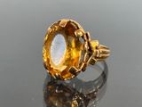 a close up of a gold ring with a large yellow stone