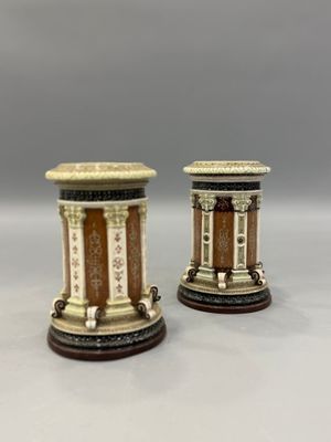 une paire de petits vases sur socles, posés sur une surface blanche