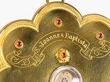 a gold plated clock with red jewels on it