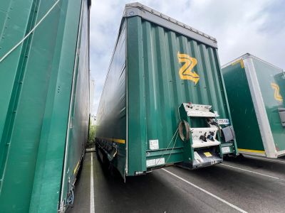 two green semi trucks that are parked on the side of the road