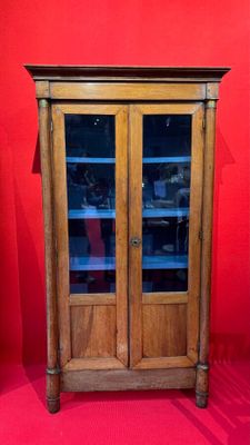 une vieille armoire en bois avec des portes vitrées et un mur rouge