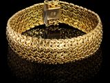 gros plan d'un bracelet en or sur une surface noire