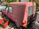 a red van that is parked next to a pile of junk
