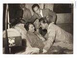 photographie en noir et blanc représentant un groupe d'hommes et de femmes dans un lit
