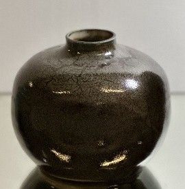 a black vase sitting on top of a glass table