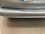 the rear end of a silver car with a sticker on it