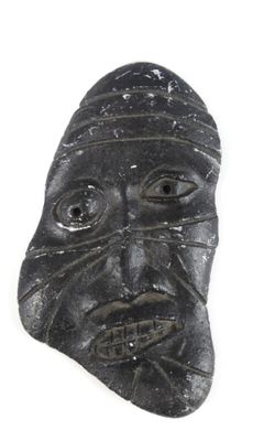 une image représentant un masque en pierre noire sur lequel est gravé un visage
