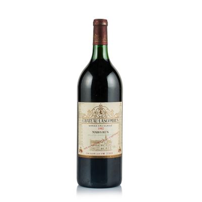 the bottle of red wine is sitting on a white surface