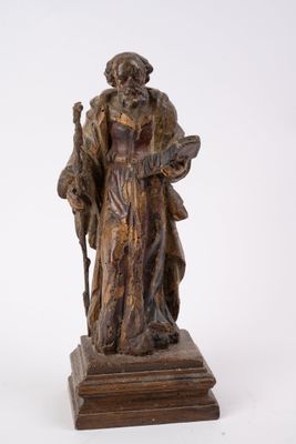 une vieille statue représentant un homme tenant un bâton, posée sur un socle en bois
