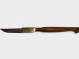 a close up of a knife with a wooden handle on a white surface
