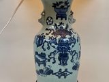 un vase bleu et blanc sur une table, avec une lampe posée dessus