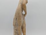 an antique statue of a boy bending over to pick something off the ground