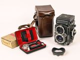 three old cameras and a case on a white surface
