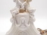 a white table lamp with two cherensils on it