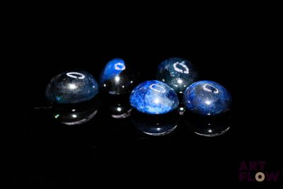 some blue and black marbles are on a black surface