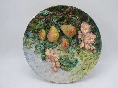 une assiette sur laquelle est représentée une peinture représentant des poires et des fleurs