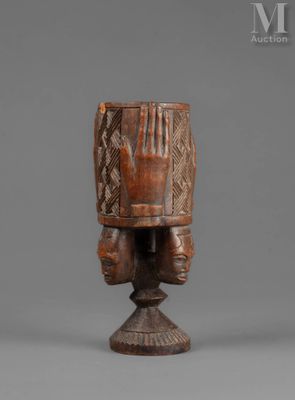 an african carved wooden headdress with two hands on it
