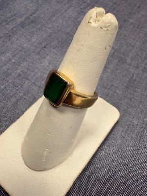 Gros plan sur une bague en or ornée d'une pierre verte