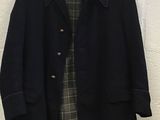 a black coat hanging on a wall next to a white brick wall