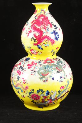 a yellow vase with a dragon on it on a black background