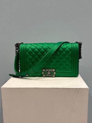 a green quilted purse sitting on top of a white box