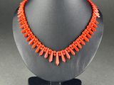 a necklace with orange beads on a black mannequin
