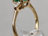 a close up of a gold ring with two emerald stones