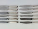 six knives are lined up in a row on a white surface