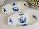 deux plats bleus et blancs posés sur une table où se trouvent des assiettes