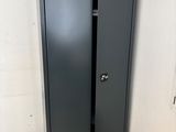 a black metal cabinet in a corner with a book on the floor