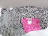 three pairs of baby girl ' s clothes on a white surface