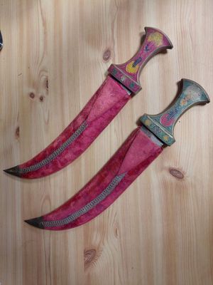 two knives are laying on a wooden surface next to each other