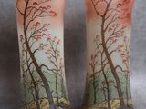 deux vases décorés d'arbres, posés sur une table