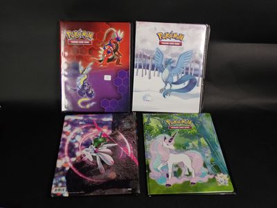 Quatre cartes Pokémon sont posées les unes à côté des autres sur une surface noire.
