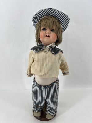 une petite poupée qui porte un chapeau et un pantalon