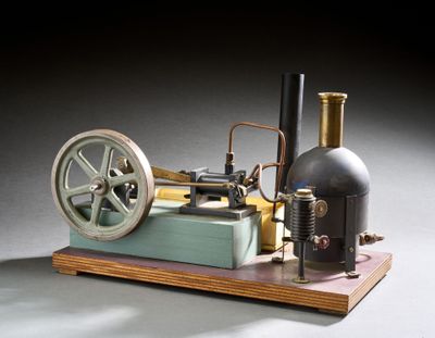 une petite maquette de machine à vapeur posée sur un socle en bois