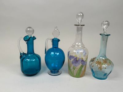 four different colored glass vases are lined up on a white surface