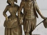 figurine en bronze représentant un homme et une femme tenant un balai