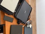 Plusieurs ordinateurs portables et autres appareils électroniques sont posés sur une table en bois