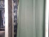 a green shower curtain hanging in a bathroom next to a toilet