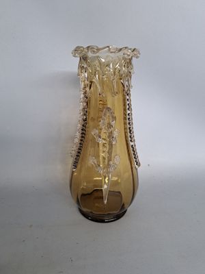 a glass vase with a chain around it on a white surface