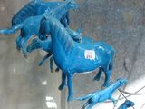 a lot of blue horses that are on display in a glass case