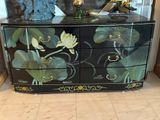 une commode noire ornée de fleurs, dans une pièce