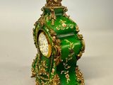 a green and gold clock sitting on a white surface