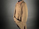 an old coat on a mannequin stand with a black background