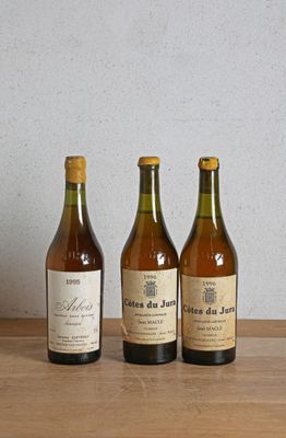 trois bouteilles de vin sont alignées sur une table en bois